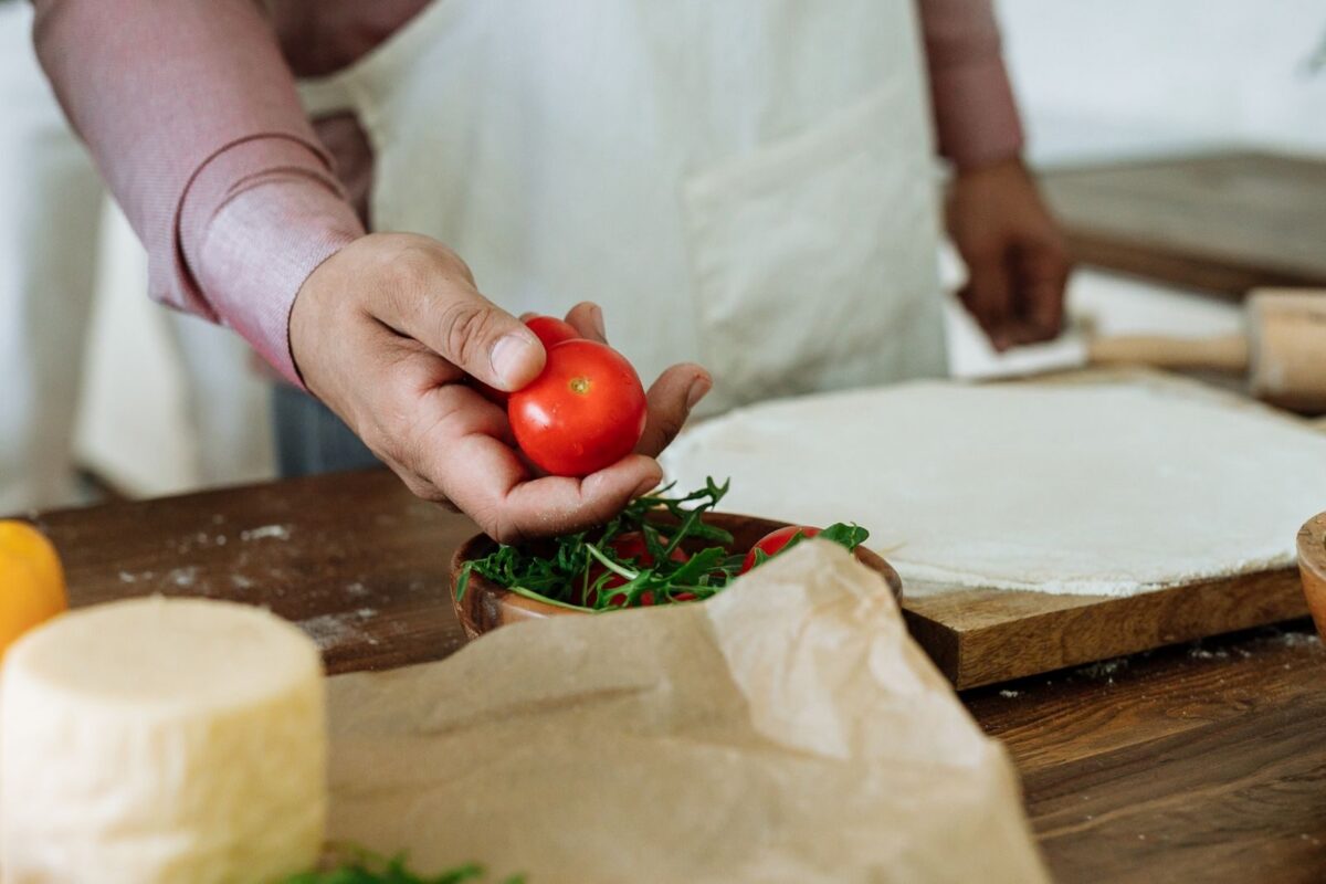 Close-up of a person holding a fresh tomato in a cozy kitchen setting, ideal for food preparation themes.